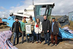 Beteiligte des Projektes vor einem Parzellenm&auml;hdrescher.